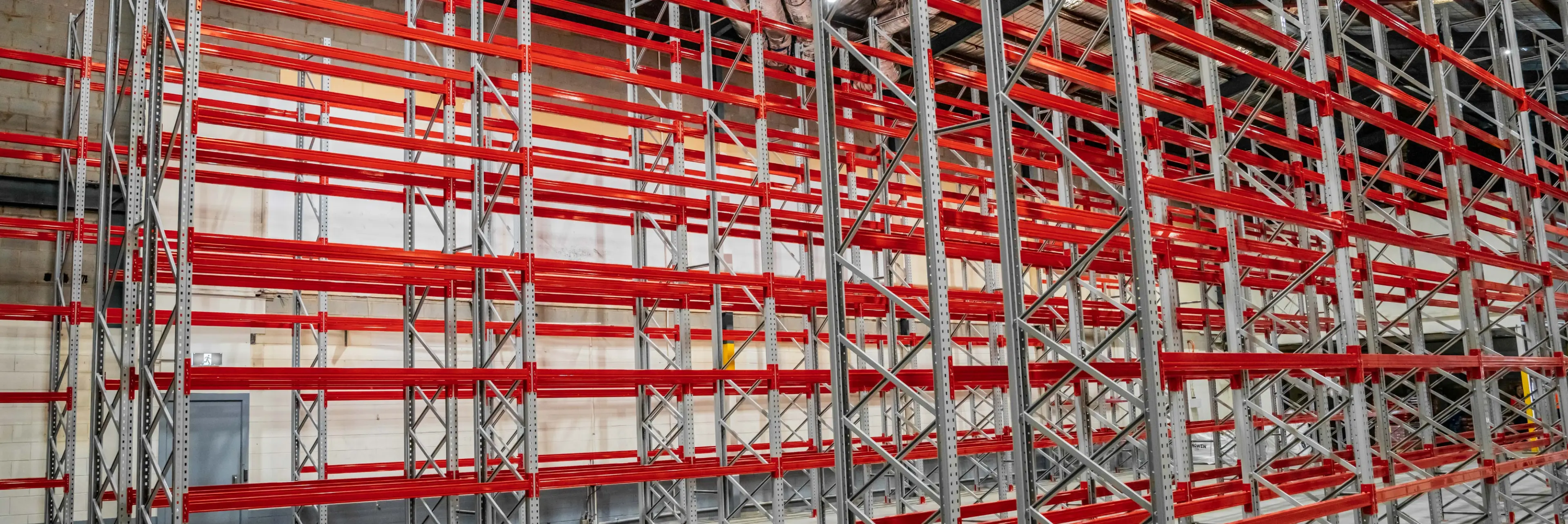 Wide-span warehouse shelving with red beams for parts storage and bulk inventory