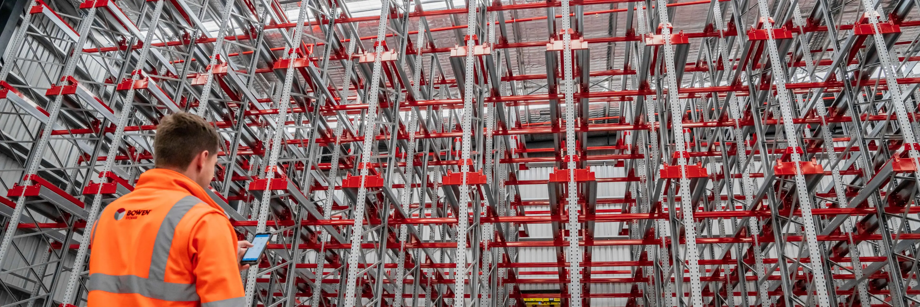 Warehouse technician inspecting high-density racking system using mobile device