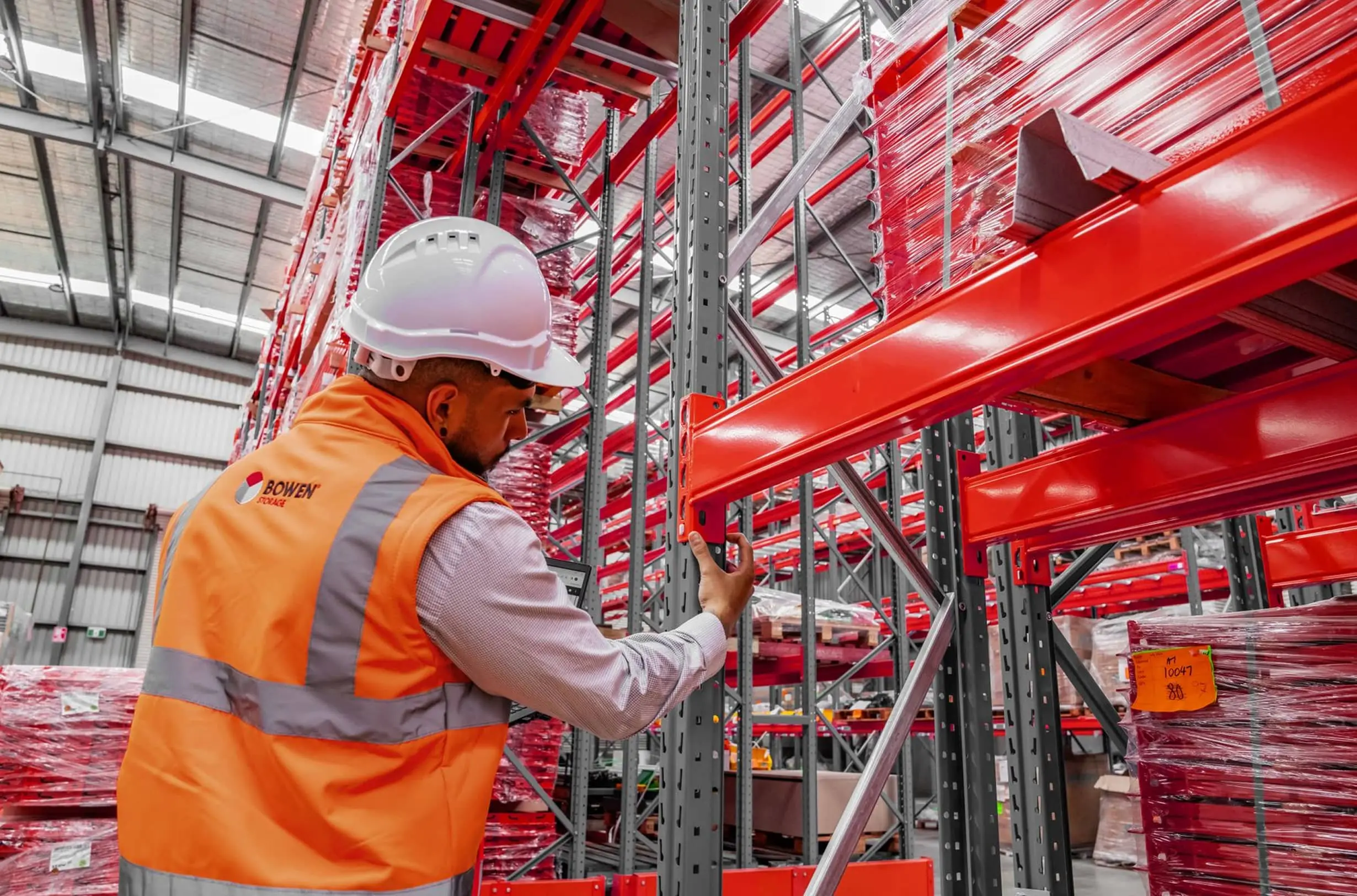 Warehouse aisle with pallet racking storing goods on pallets.