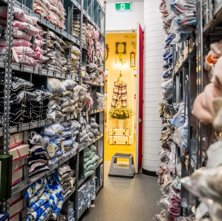Retail stockroom shelving with folded clothing and organized storage bins
