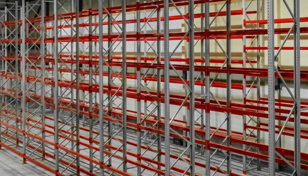 Long-span warehouse shelving system with red beams for parts storage and industrial inventory setup