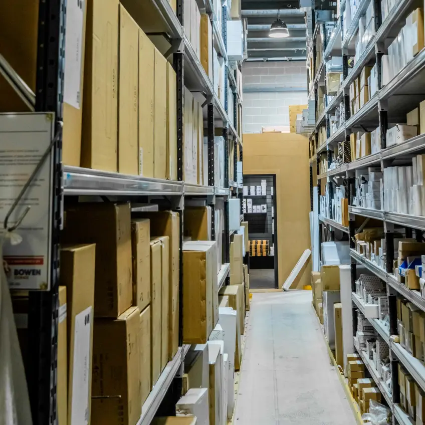 Warehouse shelving system with boxed lighting products organised in long aisle storage layout