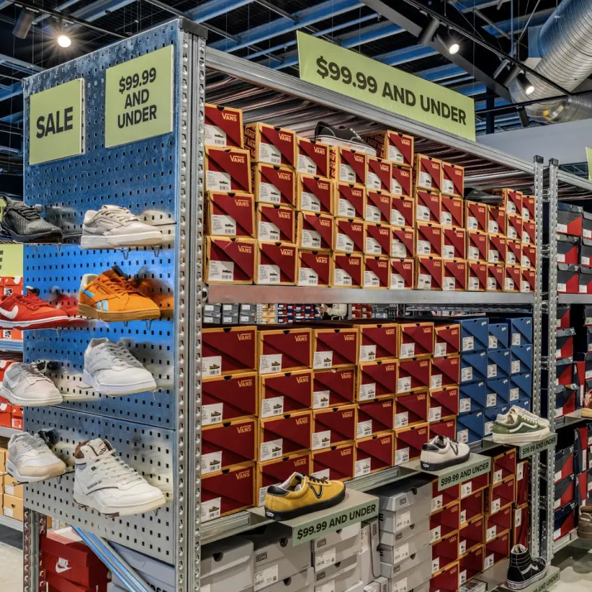Retail shelving system displaying boxed footwear with sale signage and organised product storage