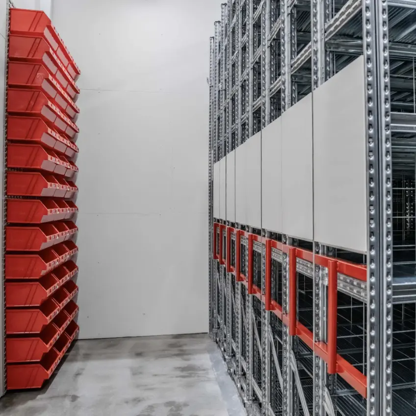 Red plastic bin storage system for small parts organisation in warehouse shelving setup