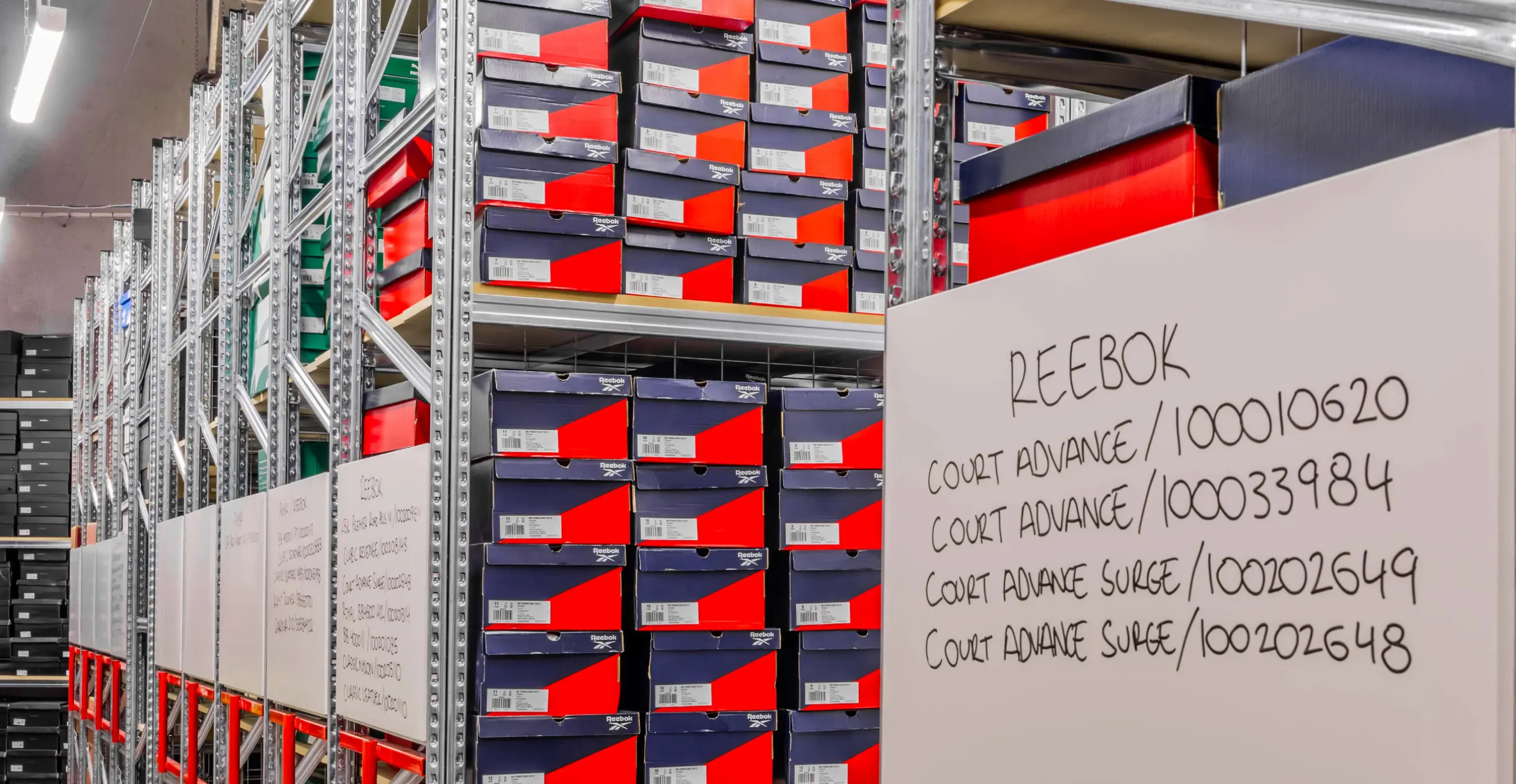 Warehouse-style retail storage with labelled shelving system and boxed footwear inventory