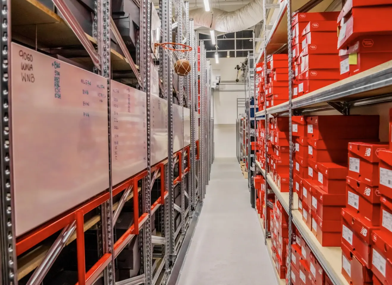 Retail warehouse shelving system with labelled inventory boards and organised footwear stockroom aisles